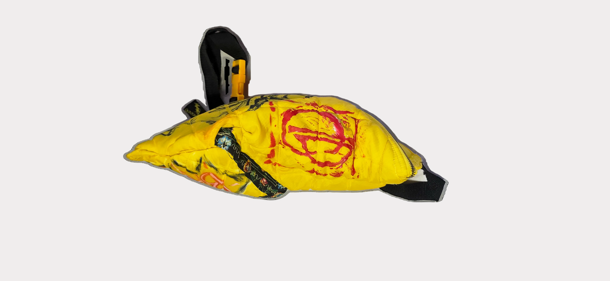 A yellow safety blindfold or face covering with black straps, a red circular symbol printed on the front, and a small yellow-and-black buckle at the top, shown on a plain white background.